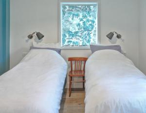 2 Betten in einem Zimmer mit einem Stuhl und einem Fenster in der Unterkunft B&B d'n Uilenhof Haren in Haren