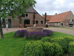 a house with purple flowers in front of a yard at B&B d'n Uilenhof Haren in Haren