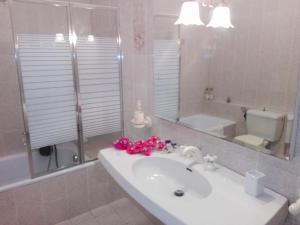 La salle de bains est pourvue d'un lavabo et de fleurs roses. dans l'établissement A Casa Mia, à Cascina