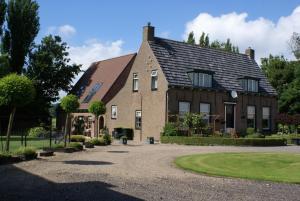 une grande maison en briques avec une allée en gravier dans l'établissement Bed & Breakfast de Kienstee, à Schoondijke