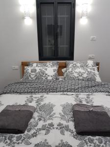 1 cama con edredón y almohadas en blanco y negro en Shahen's Boutique Apartment By Ahlan Hospitality en Tarshīhā