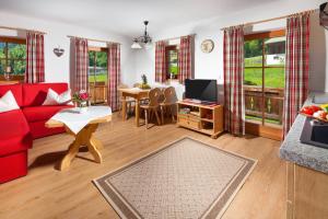 a living room with a red couch and a table at Ferienwohnung Hafnerlehen - wohnen mit Seeblick in Schönau am Königssee