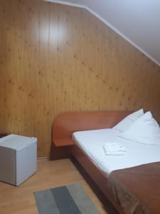 um quarto com uma cama e uma parede de madeira em Pensiunea Valea Negrasului em Trăisteni