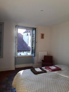 1 dormitorio con 1 cama y ventana con silla en Galerie Benjamine, en Vézelay