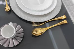a table with goldware and a plate and a gold spoon at Sea Elegance in Oliveri