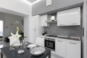 a kitchen with white cabinets and a table with a sink at Sea Elegance in Oliveri