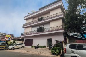 un bâtiment blanc avec des voitures garées devant lui dans l'établissement Clean & Comfort Homestay, à Ambon