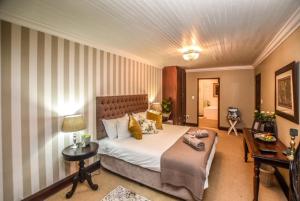 ein Hotelzimmer mit einem Bett, einem Tisch und einem Schreibtisch in der Unterkunft The Aloes in Nelspruit