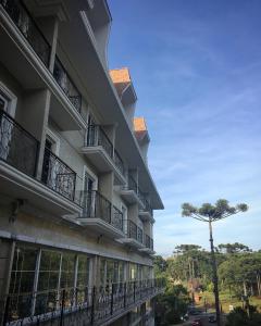 a large building with balconies and a tree at Hotel Daara in Gramado