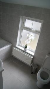 a bathroom with a toilet and a window with flowers at Belmullet Townhouse in Belmullet +9 photos