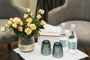 a table with a vase of flowers and two bottles of wine at Teryan Pushkin Apart Hotel in Yerevan