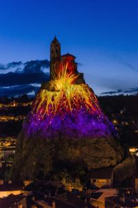 Un grand rocher avec un château en haut le soir dans l'établissement studio - baignoire - prêt de vtt - lave linge, au Puy-en-Velay