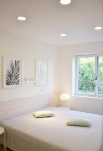 een witte slaapkamer met een bed met 2 kussens erop bij Lieblingsplatz Neusiedl Appartement - Entspann dich in Neusiedl am See