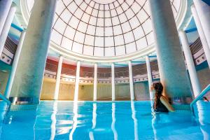 una mujer sentada en el agua de una piscina en Blau Hotel Las Caldas, en Las Caldas