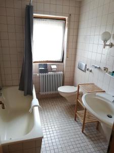 a bathroom with a tub and a toilet and a sink at Gästehaus Rössle in Rötenbach