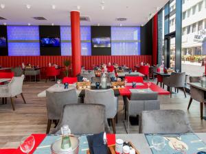 a restaurant with tables and chairs and a large screen at DORMERO Hotel Salzgitter in Salzgitter