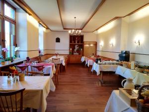 une salle à manger avec des tables et des nappes blanches dans l'établissement Gästehaus Rössle, à Rötenbach