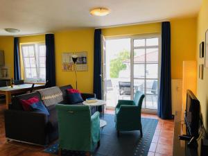 ein Wohnzimmer mit einem Sofa, Stühlen und einem TV in der Unterkunft Villa Sanddorn in Binz