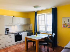 eine Küche mit einem Tisch und eine Küche mit gelben Wänden in der Unterkunft Villa Sanddorn in Binz