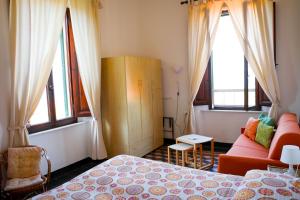 ein Schlafzimmer mit einem Bett, einem Sofa und Fenstern in der Unterkunft Albergo Pensione Bartoli in Castiglioncello