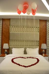 Una cama con un corazón hecho de globos rojos en E1 Hotel en Al Kharj