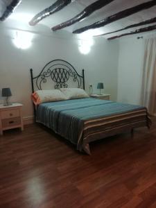1 dormitorio con 1 cama grande en una habitación con suelo de madera en La Troya, en Castellote