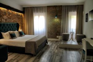 
a hotel room with a bed, chair, and nightstand at Art'Otel Barcelos in Barcelos
