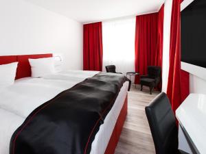 Una habitación de hotel con una cama grande con cortinas rojas. en DORMERO Hotel Salzgitter, en Salzgitter