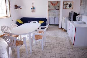 uma cozinha com uma mesa e cadeiras brancas e um sofá em Casa Gelso em Punta Prosciutto