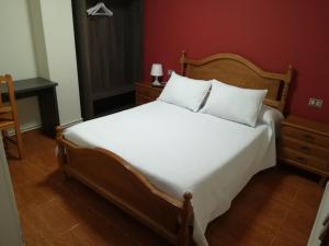 sypialnia z dużym białym łóżkiem i czerwoną ścianą w obiekcie Pensión Restaurante Casa Camiño II w mieście Palas de Rei 