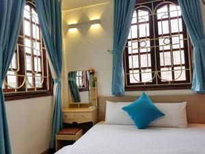 a bedroom with a bed and two windows with blue curtains at Hanowood Homestay - Renovated since June 2026 in Hanoi