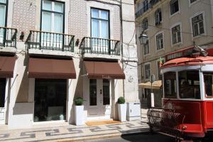 a red trolley car parked in front of a building at Lisboa Prata Boutique Hotel in Lisbon