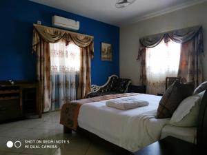 a bedroom with a large bed with blue walls and windows at Hotel Golden House in Antsiranana