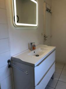 La salle de bains blanche est pourvue d'un lavabo et d'un miroir. dans l'établissement maison de pêcheurs, à Saint-Michel-en-Grève