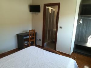 a bedroom with a bed and a desk and a chair at Pensión Restaurante Casa Camiño II in Palas de Rei