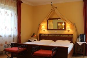 een slaapkamer met een hemelbed met een spiegel en 2 stoelen bij Gasthaus Beinker in Ostercappeln