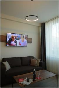 a living room with a couch and a tv on the wall at Motel Plus Schönefeld in Schönefeld