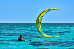 a man in the ocean with a kite at Pousada Costa Prestige in Touros