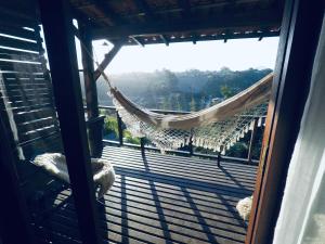 un balcón con hamaca y vistas en Casa Fluila en Praia do Rosa