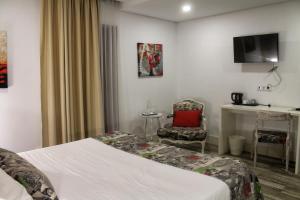 
a room with a bed, a desk and a television at Art'Otel Barcelos in Barcelos
