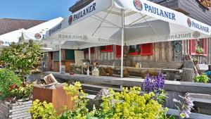 ein Restaurant mit einem Sonnenschirm, Stühlen und Blumen in der Unterkunft Zur grossen Tanne in Bühl