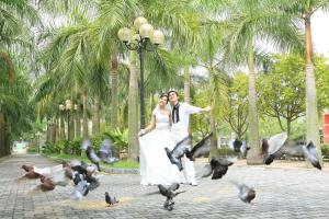 a bride and groom standing in front of a flock of birds at Camela Hotel & Resort in Hai Phong