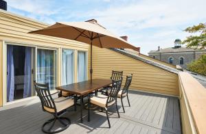 a wooden table with chairs and an umbrella on a balcony at Vine Village Apartments in Niagara on the Lake