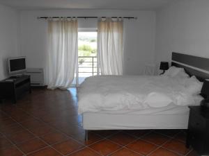 a bedroom with a white bed and a television at Monte das Matas in Monsaraz