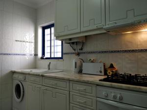 a kitchen with white cabinets and a sink and a stove at Oceanides Beachfront Apartments in Quarteira