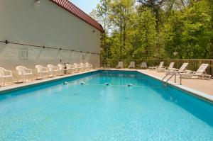 une piscine avec des chaises et un bâtiment dans l'établissement Motel 6-Gatlinburg, TN - Smoky Mountains, à Gatlinburg