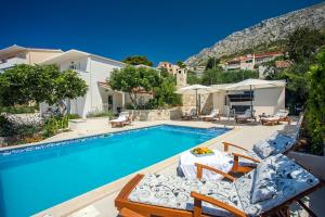 Una piscina con dos tumbonas y una casa. en Villa Dasianda - only 90 m from the beach, private 30msq heated pool, en Stanići