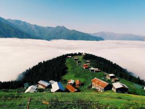 a group of houses on a hill above a field of clouds at POKUT orion in Çamlıhemşin