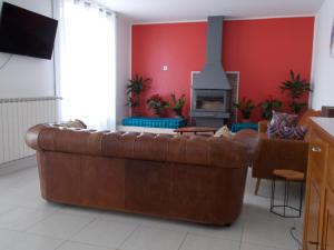 a living room with a brown leather couch and a fireplace at La Maison Lydia in Moissac