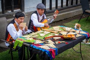 two men sitting at a table with a guitar at Rondador Cotopaxi in Chasqui